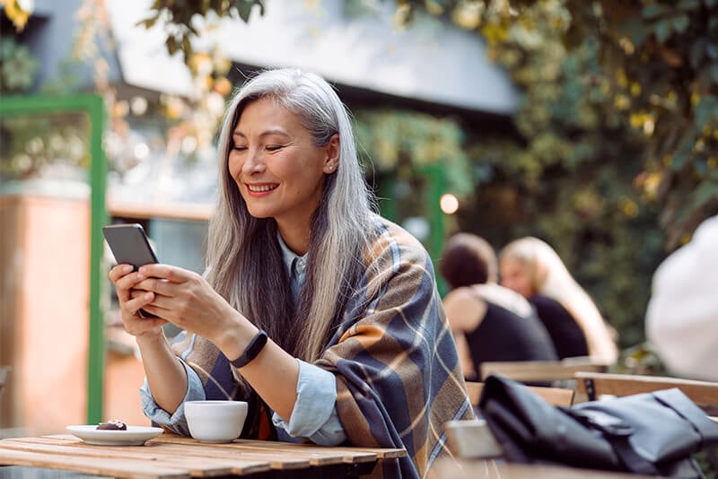 Smiling women sitting outside looking at phone